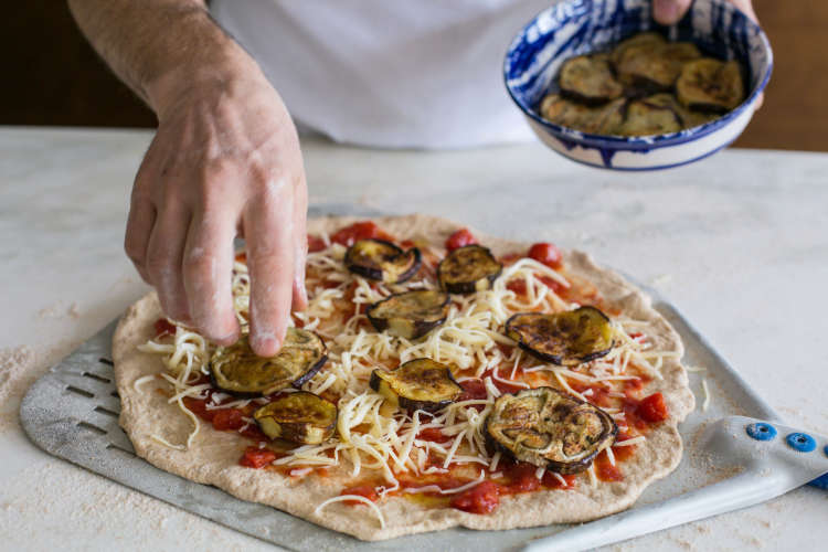 chef topping an eggplant pizza during a cooking class