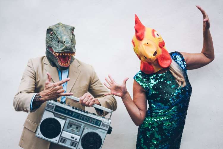 coworkers wearing dinosaur and chicken masks at a themed costume party