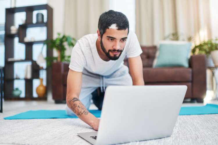 man setting up computer to take online yoga class