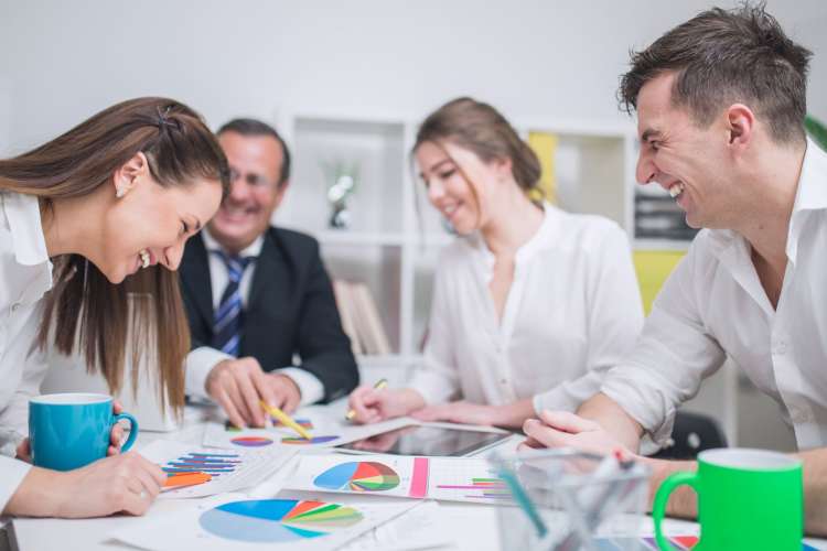 a group of professionals smiles over pie charts