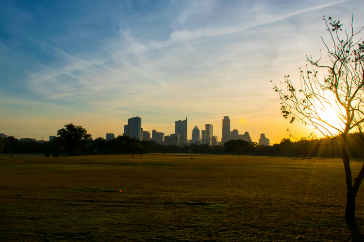 zilker park at sundown with the austin skyline in the background