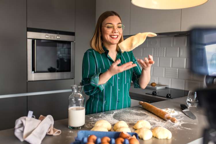 woman tossing pizza dough in her kitchen