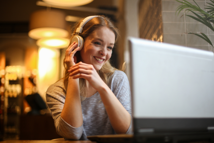 woman with headphones playing name that tune on a laptop