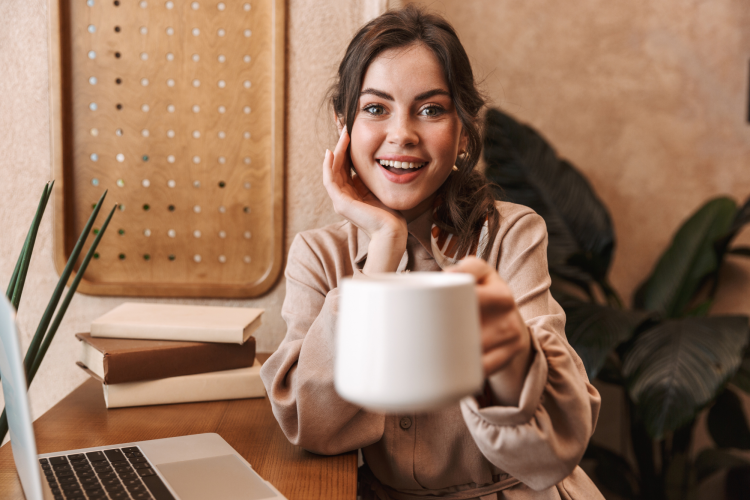 young woman holding a mug of coffee while sitting at a desk