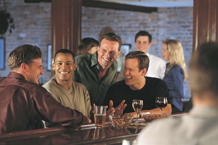 group of guys drinking beer and chatting at a bar