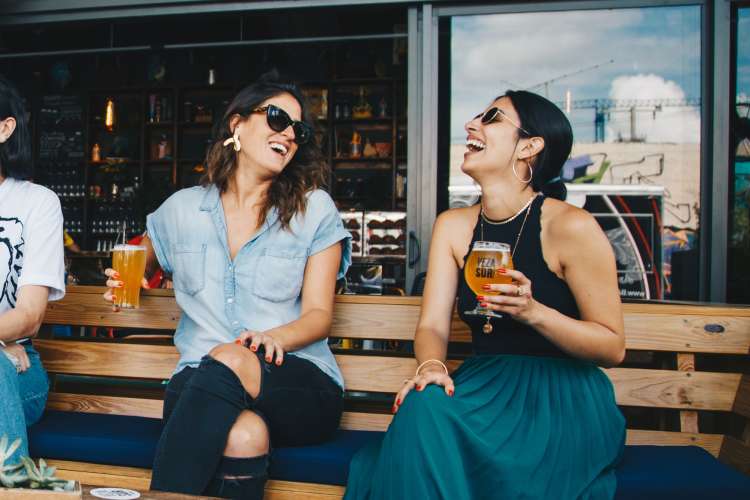 women drinking beer outside of bar
