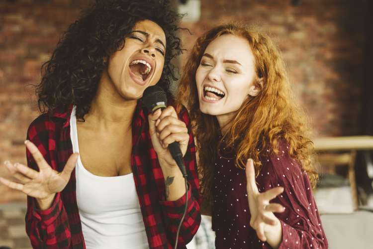 two women singing karaoke in microphone