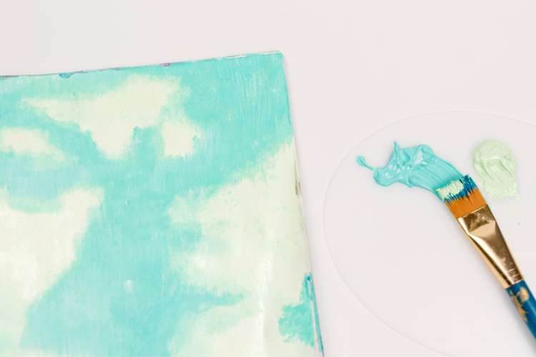 blue paint and paintbrush next to white clouds on canvas