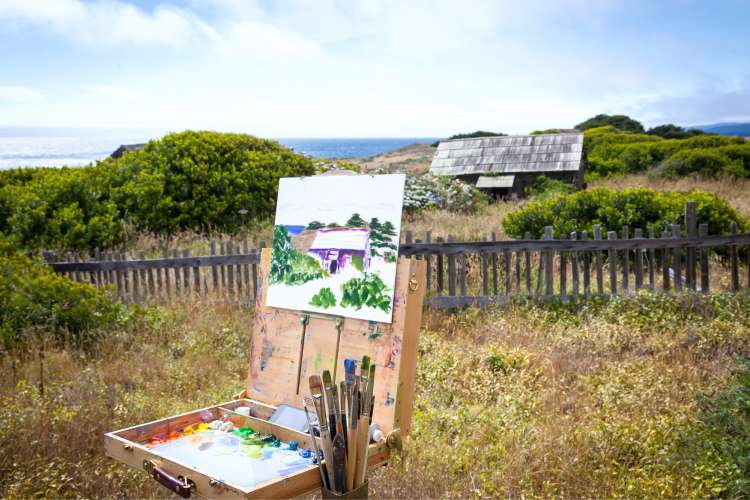 canvas on easel painting in countryside with house