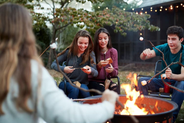 Teenage Friends Making S'Mores over a campfire.
