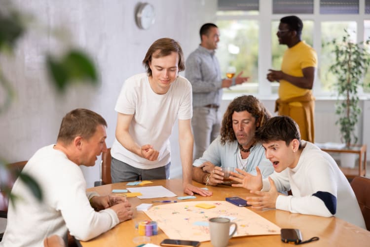 a group of men gather around a board game and play together