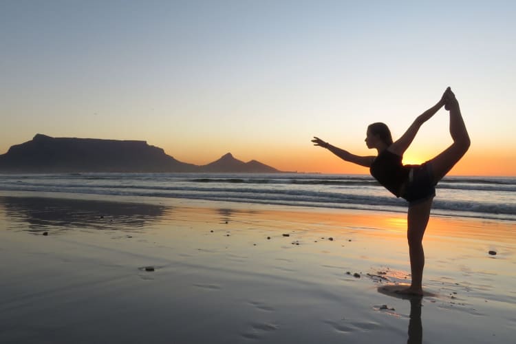 Silhouette of woman doing yoga at the beach