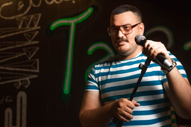 a comedian stands with a microphone ready to deliver his next line