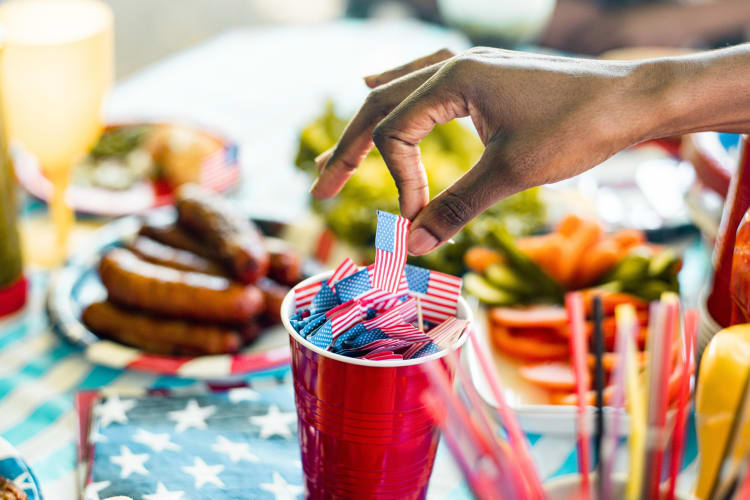 A person taking a small US flag from a cup at a barbecue