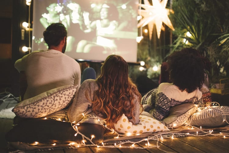 Four people watching a movie outdoors at night