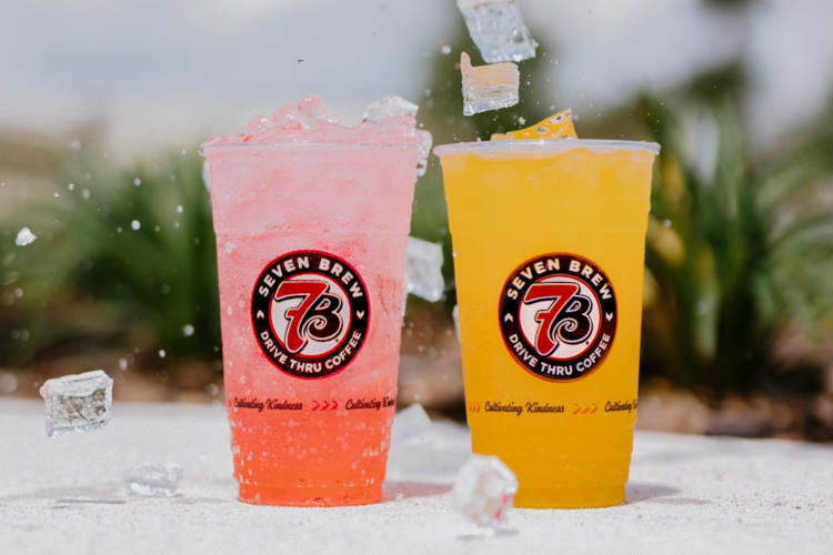 A pink drink and an orange drink next to ice