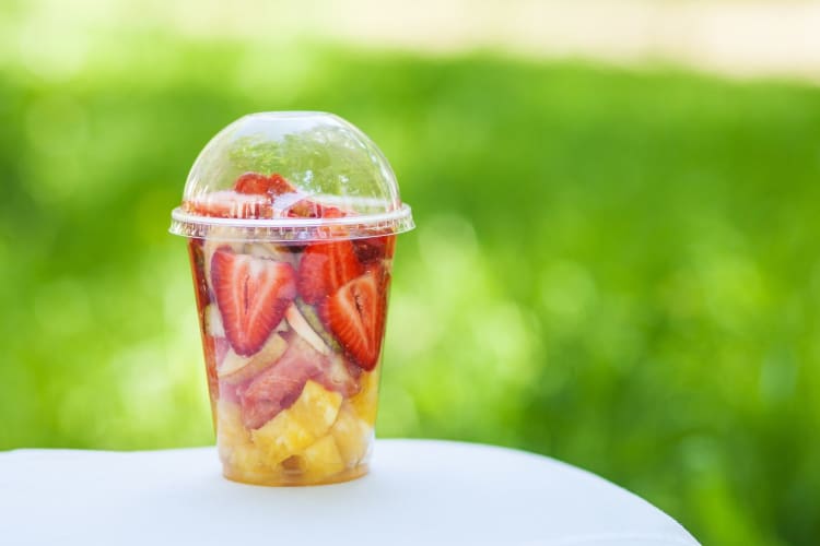 Sliced fresh fruits in a plastic cup.
