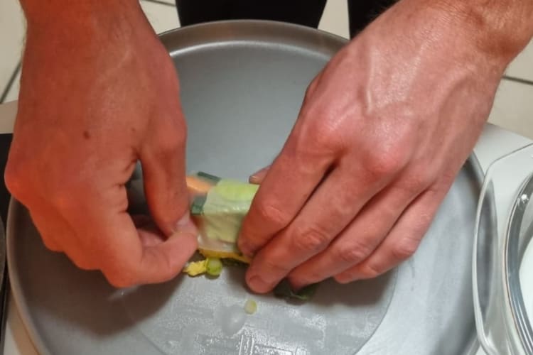 Hands rolling a vegan Thai spring roll in rice paper