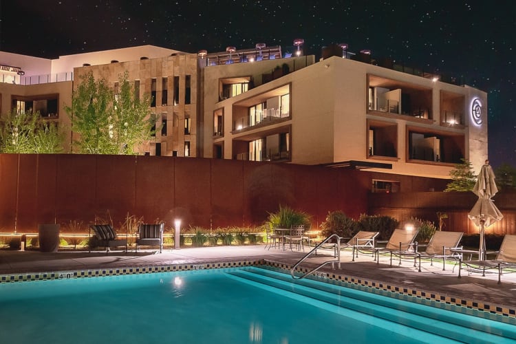 A pool next to a hotel building at night