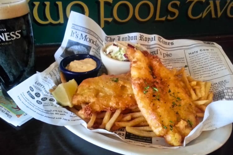 A plate of fish and chips and a pint of Guinness on a pub table