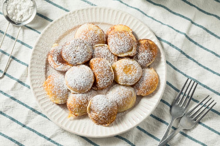 Mini pancakes on a plate dusted with powdered sugar