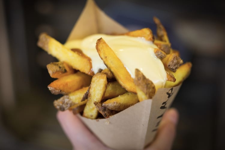 A paper cone with fries and mayonnaise