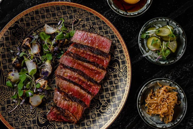 Aerial shot of steak cutlets with sides in different bowls from Animae