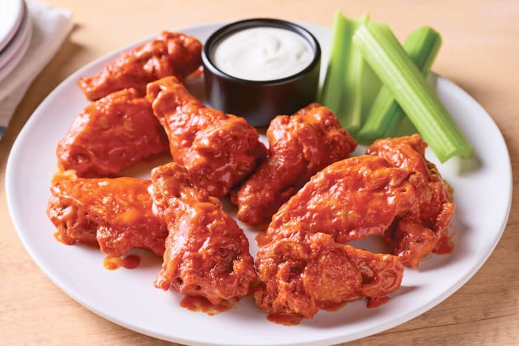 Buffalo chicken wings on a plate with celery and dip