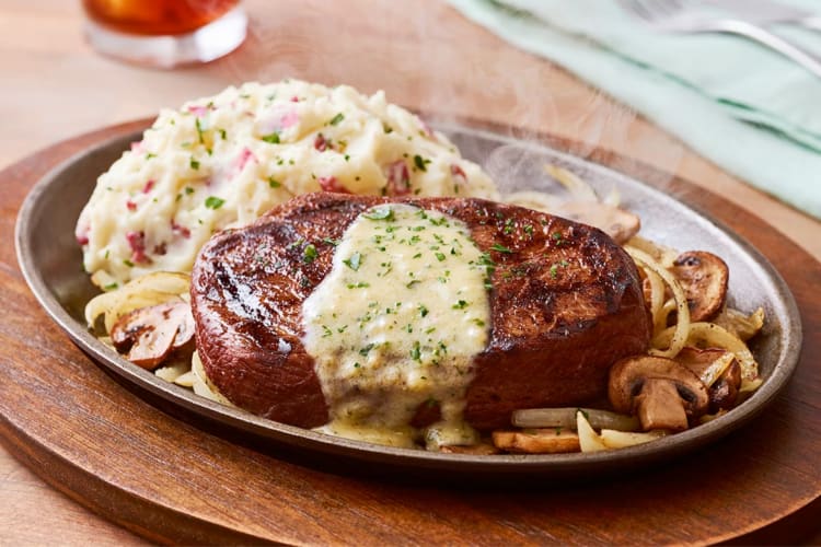 A steak with garlic butter next to mashed potatoes and