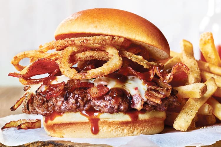 A burger with onion rings, cheese and bacon