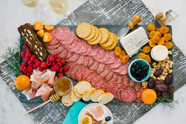 A charcuterie board with meats, crackers and fruits