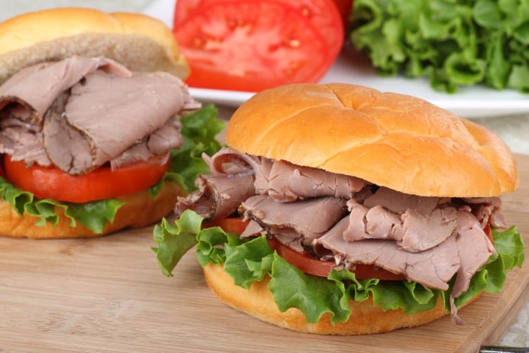 A roast beef sandwich with tomato, lettuce and onion