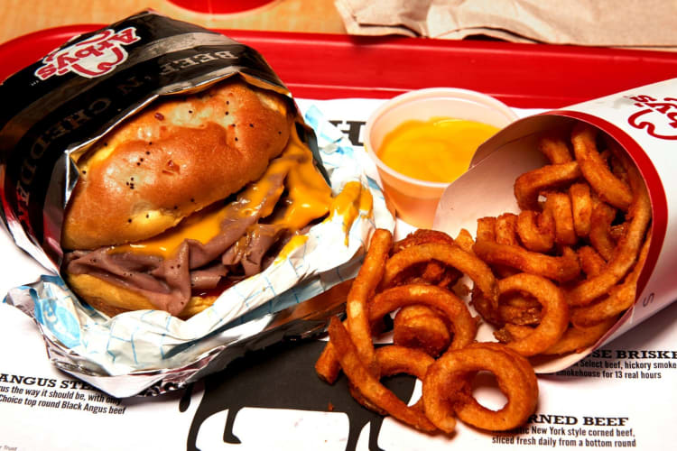 A roast beef sandwich and curly fries on a tray