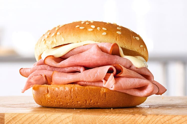 A ham and Swiss sandwich on a wooden surface