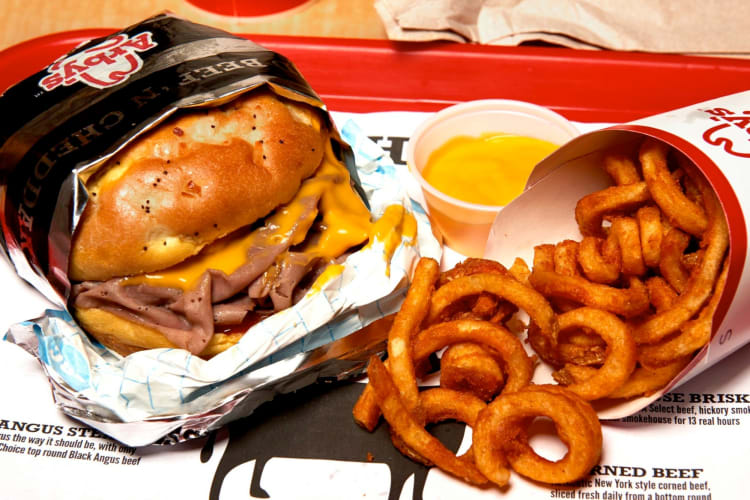 A roast beef sandwich and curly fries on a tray