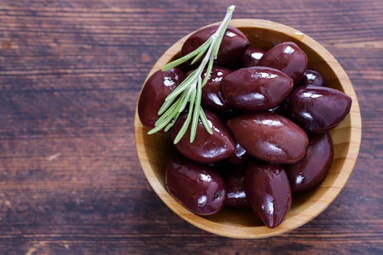 Kalamata olives in a bowl on a wooden surface