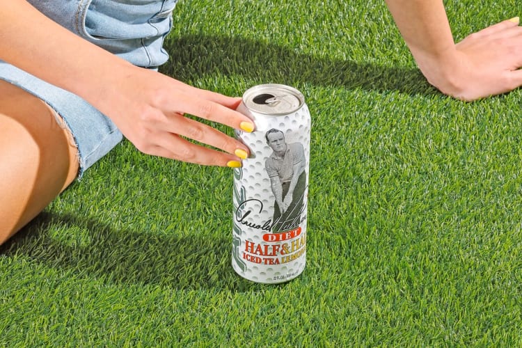 A person on the grass with a can of Arizona Diet Arnold Palmer
