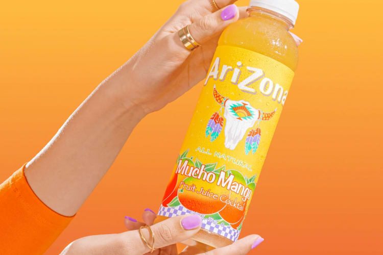 A person holding a bottle of Mucho Mango Arizona iced tea