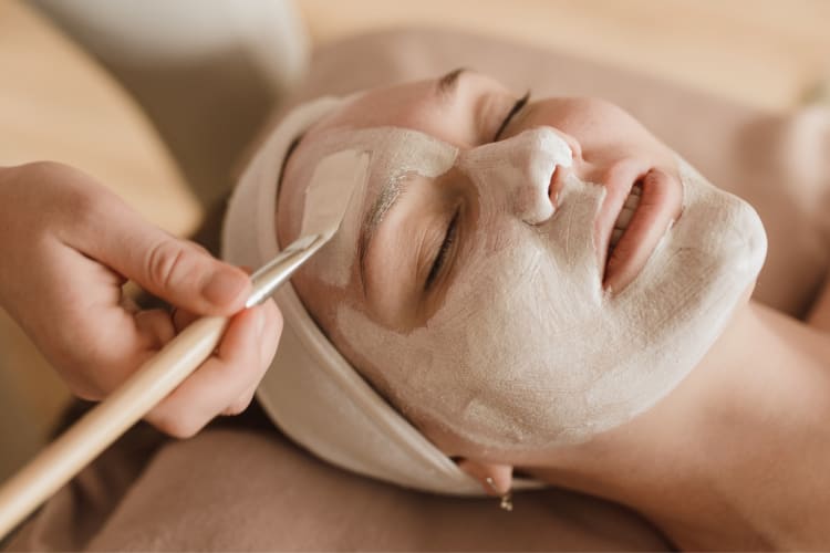 A woman at the spa getting a face mask applied
