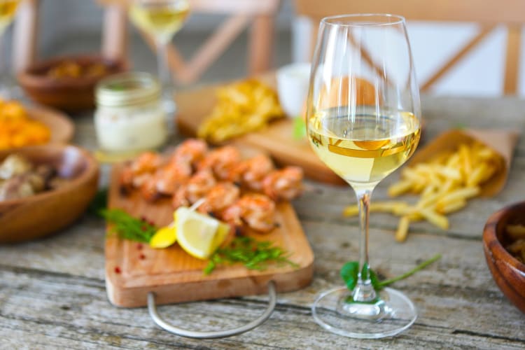 A glass of wine next to seafood on wooden boards