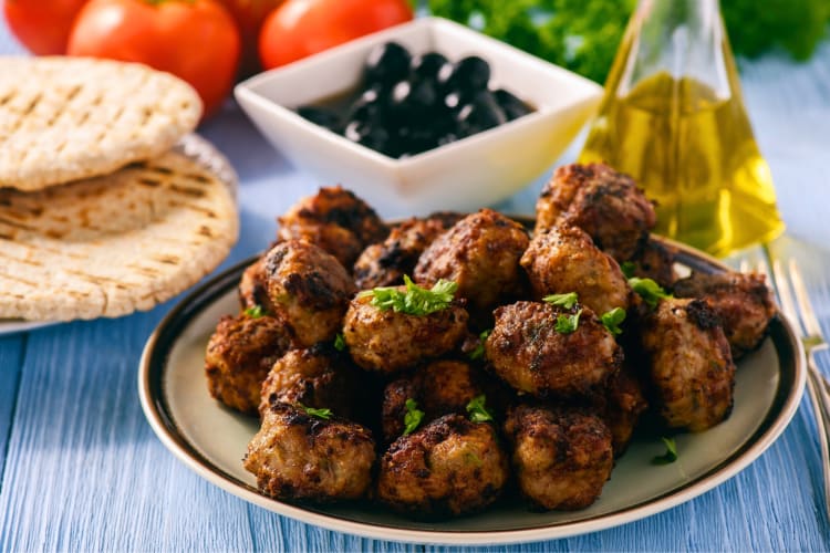 Greek meatballs on a plate next to pita bread