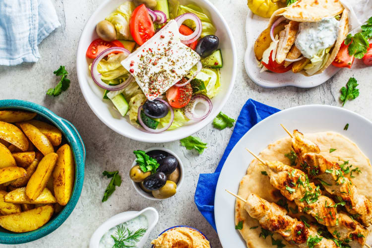 Greek salad, potatoes and chicken on a table