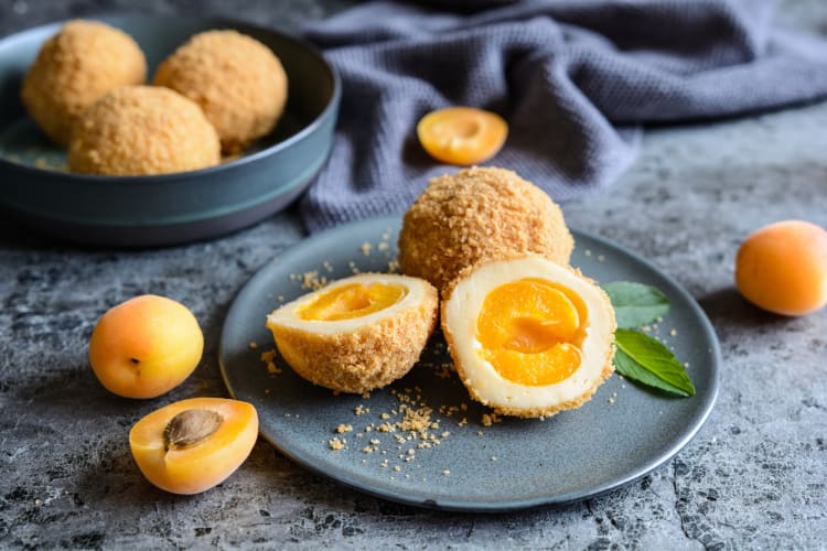 Marillenknödels on a white plate — a delicious Austrian food eaten as a dessert