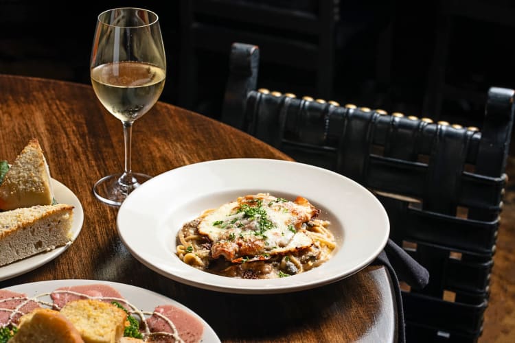 Pasta dish next to a glass of wine from Aventino’s Italian Restaurant