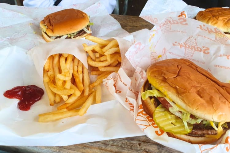 Three cheese burgers with fries. 