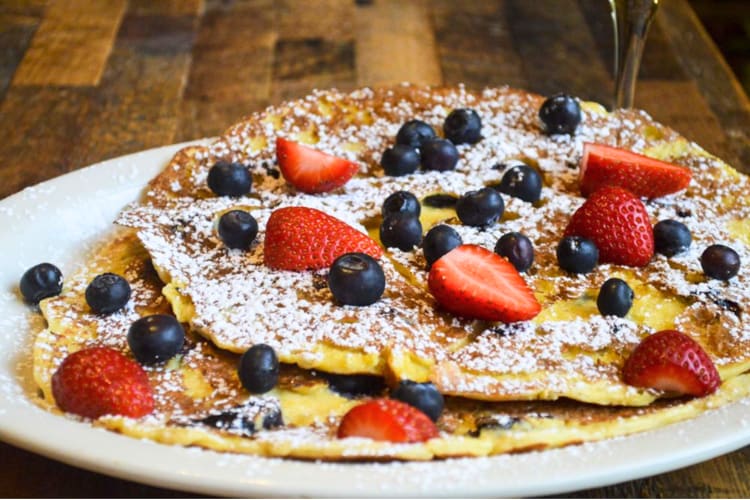 Blueberry corn pancakes topped with strawberries and icing sugar is on offer at this breakfast spot in Minneapolis.