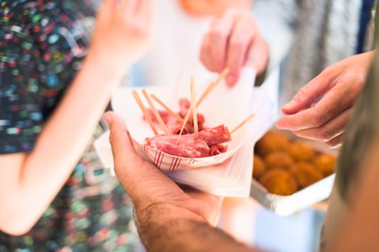 People trying salami together on a food tour team building activity in London. 