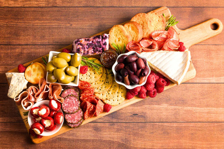 This dinner party theme idea is charcuterie board topped with cheese, grapes and berries.
