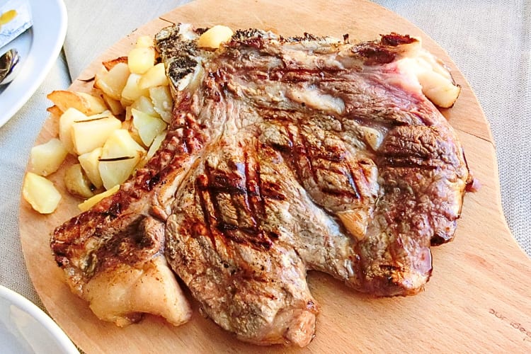  Bistecca alla Fiorentina is a Florence food that is a steak with a crusty exterior. This one is served with potatoes. 