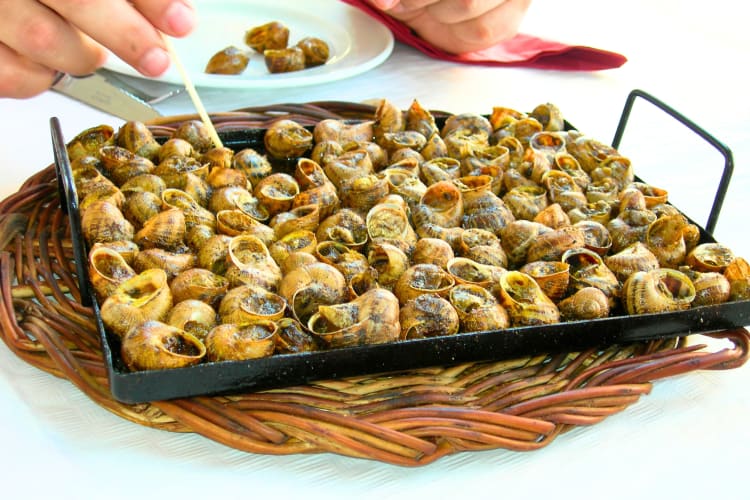 This Barcelona food features snails cooked in a tin tray, often roasted in the oven or on a barbecue. 